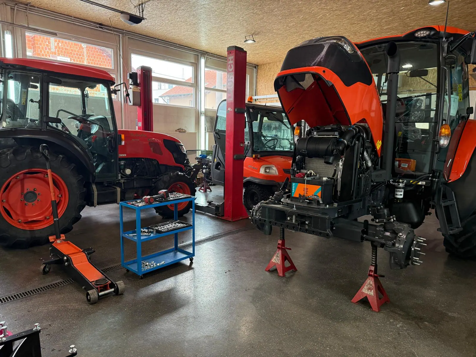 Kubota traktor s podignutom haubom na stalcima u servisnoj radionici Se-Kra