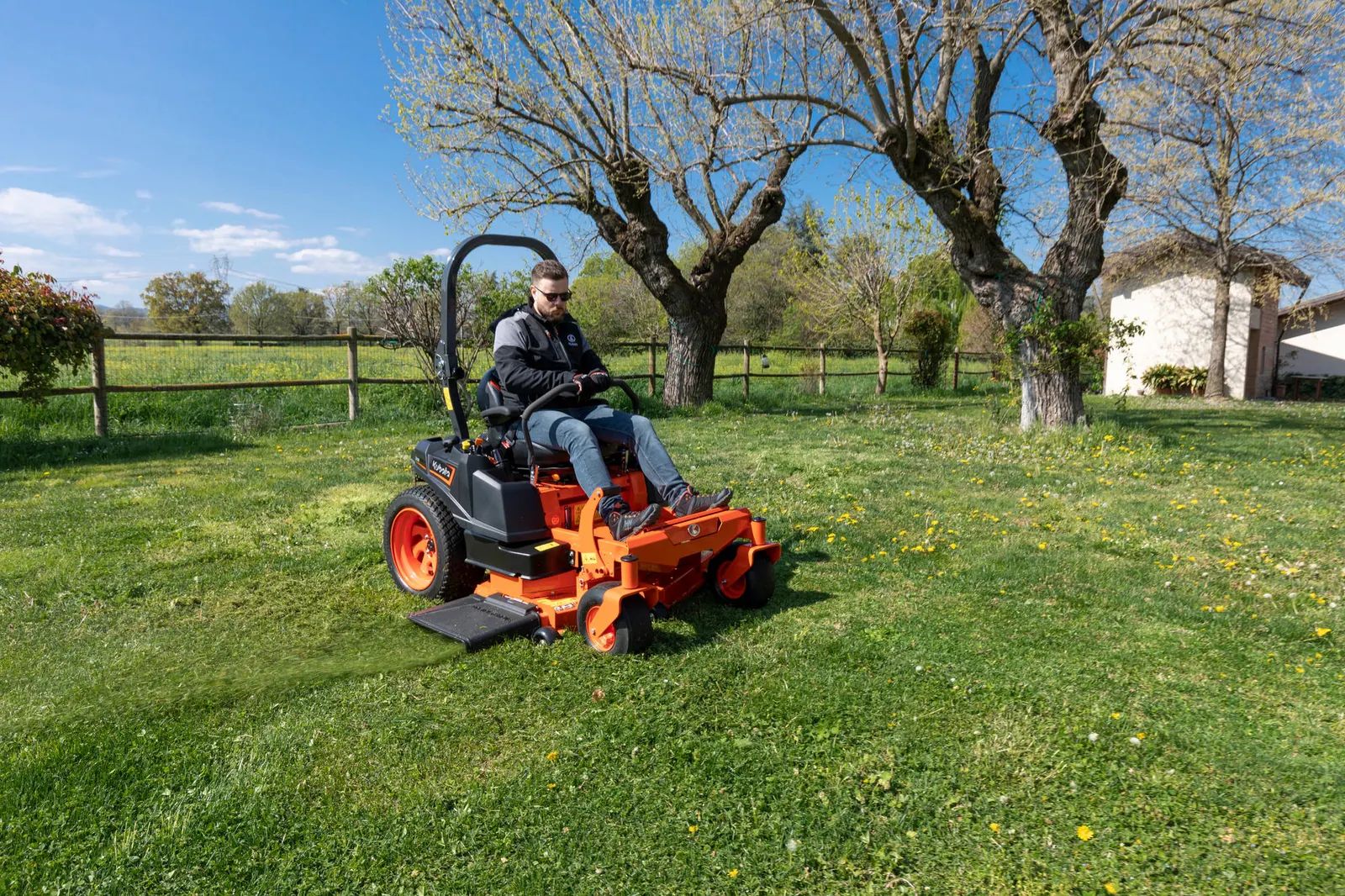 Kubota Z2-481 kosi travnjak među stablima, vozač upravlja dvjema ručicama