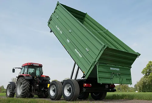 Brantner tandem kiper s visoko podignutim sandukom, prikopčan na crveni traktor na poljskom putu