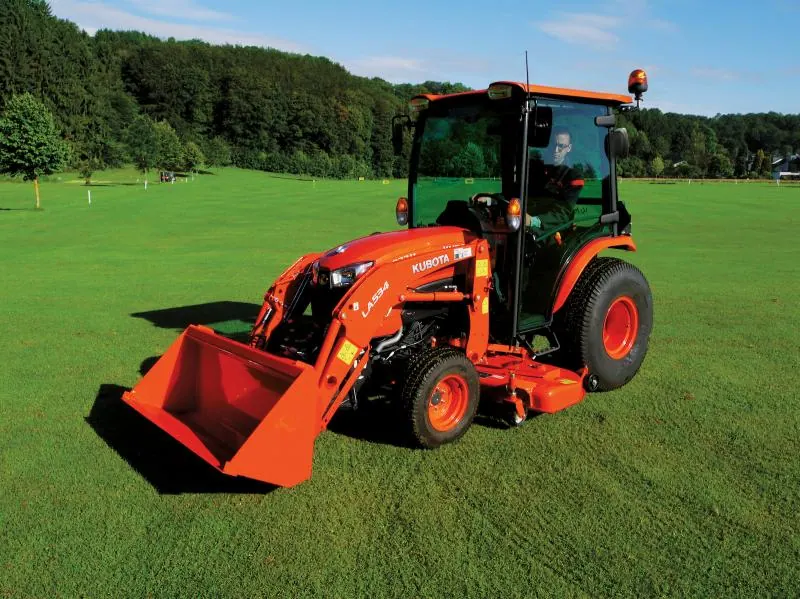 Kubota B2 s kabinom, prednjim utovarivačem LA534 i središnjom kosilicom na travnjaku