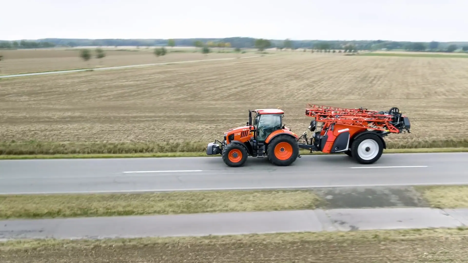 Kubota traktor M7 s vučenom prskalicom na cesti uz polje