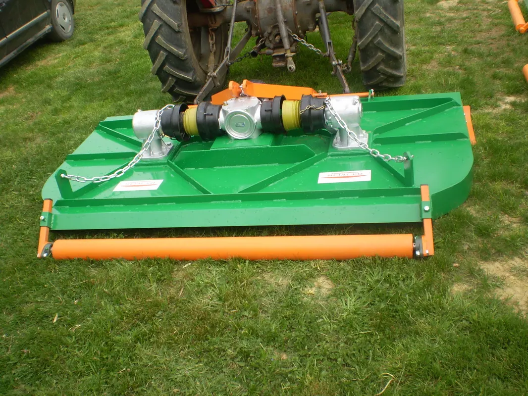 Metal-KO rotacijski malčer RM priključen na traktor, zeleno kućište i narančasti stražnji valjak, na travi